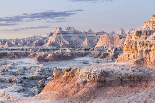 A stunning landscape of rugged rock formations and layered cliffs at sunrise, showcasing the Badlands' unique geology.