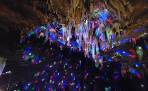 A colorful cave interior with illuminated stalactites and a sparkling floor, creating a vibrant, magical atmosphere.