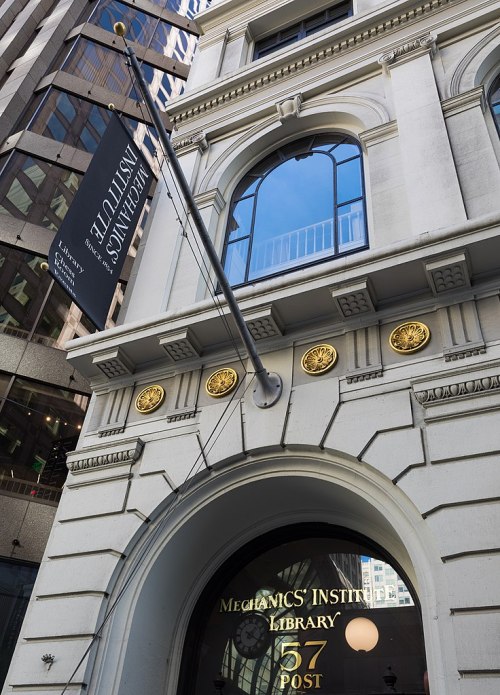 Historic building facade featuring a library entrance with decorative elements and a sign for the Mechanics' Institute.