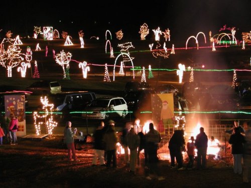 A festive scene with colorful holiday lights and people gathered around a fire, enjoying a winter celebration.