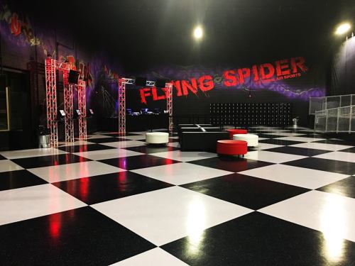Interior of a trampoline park named "Flying Spider," featuring a checkered floor and colorful seating areas.