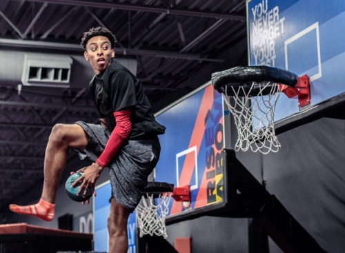A young athlete performs a slam dunk on a basketball court, showcasing agility and skill.