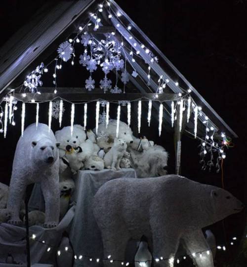A festive display featuring white polar bear decorations and snowflakes, illuminated by string lights in a dark setting.