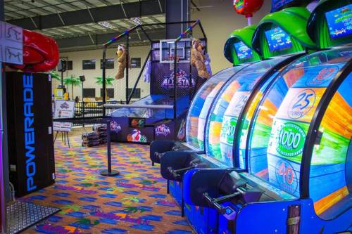 Colorful arcade with slot machines, a basketball game, and vibrant flooring in a lively entertainment center.
