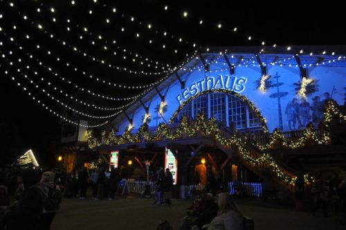 A festive building adorned with lights and decorations, bustling with people during a nighttime event.