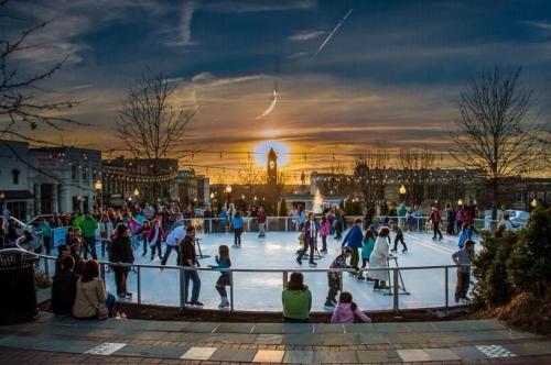 A vibrant ice skating rink at sunset, filled with skaters and spectators enjoying the winter evening.
