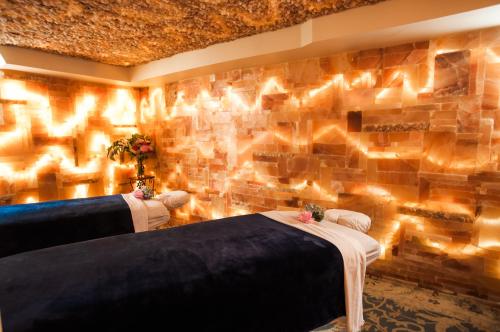 A serene spa room with two massage tables, illuminated by warm lights and a salt wall in the background.