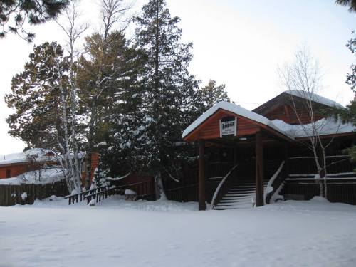 A cozy wooden lodge surrounded by snow-covered trees and a winter landscape.