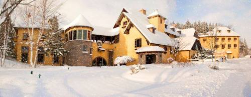 A picturesque yellow building surrounded by snow-covered trees and a snowy landscape, under a cloudy sky.