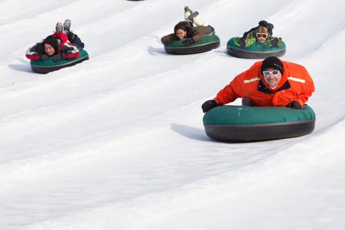 A group of people tubing down a snowy slope, enjoying a winter day.