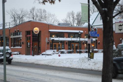 A cozy brick building with large windows, covered in snow, on a winter street corner.
