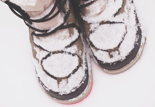 Close-up of snow-covered boots standing on a snowy surface.