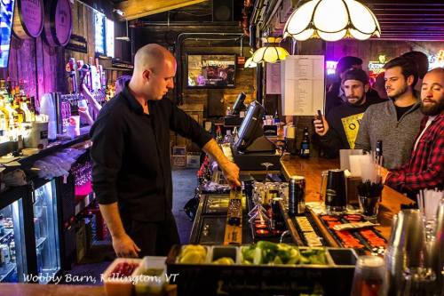 A bartender prepares drinks at Wobbly Barn in Killington, VT, while patrons watch and socialize at the bar.