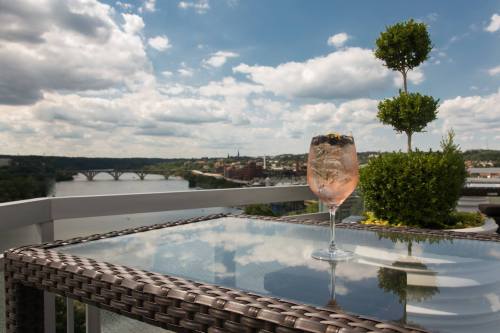 A refreshing drink sits on a glass table with a scenic view of a river and cloudy sky in the background.