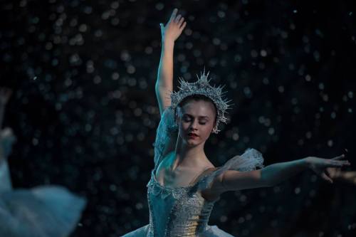 A ballet dancer in a sparkling costume gracefully performs, surrounded by a flurry of soft, shimmering lights.