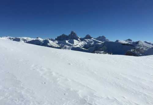 Snow-covered mountains under a clear blue sky, showcasing a serene winter landscape.