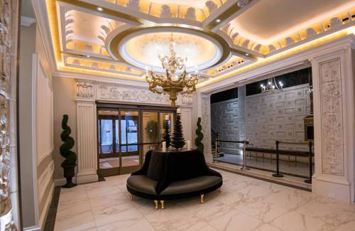 Luxurious lobby with ornate ceiling, chandelier, and a black circular sofa, featuring elegant decor and marble flooring.
