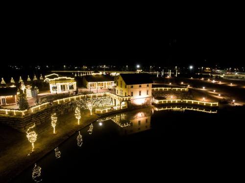 A beautifully lit house and garden at night, adorned with festive lights reflecting in the water.