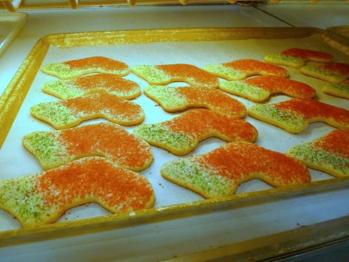 A tray of colorful cookies shaped like letters, topped with red and green sprinkles.