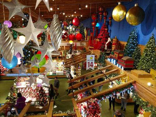 A festive store filled with Christmas trees, ornaments, and decorations, featuring colorful lights and holiday displays.