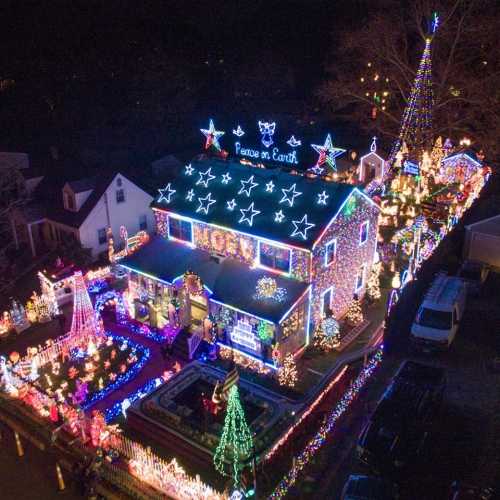 Aerial view of a brightly lit house decorated with colorful Christmas lights and festive displays.