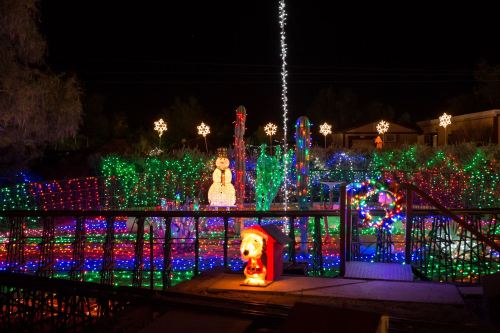 A colorful display of Christmas lights featuring a snowman, stars, and festive decorations in a nighttime setting.