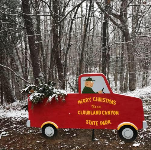 A festive red truck with a Christmas tree, set in a snowy forest at Cloudland Canyon State Park.