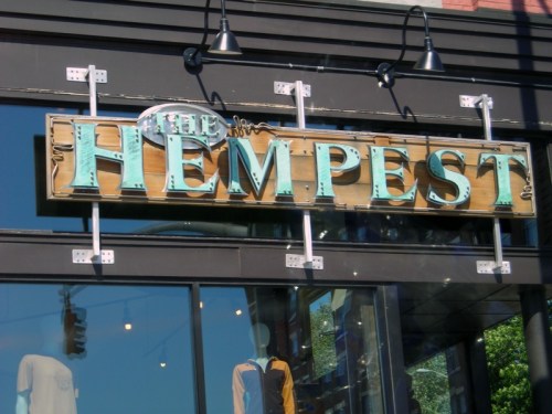 Sign for "The Hemp Pest" store, featuring bold letters and a rustic wooden background.