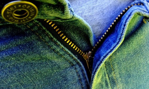 Close-up of a partially zipped denim jacket, showcasing the zipper and fabric texture.