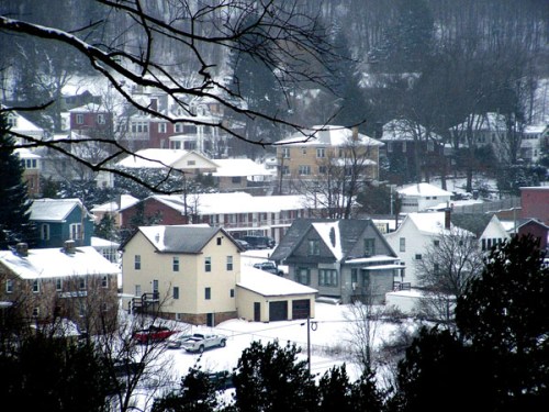 A snowy landscape featuring a cluster of houses nestled among trees in a quiet neighborhood.