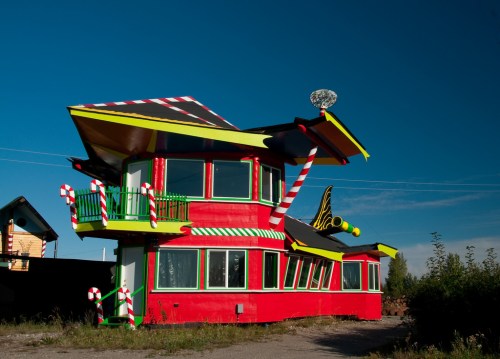 A whimsical, colorful house with candy cane accents and a unique, playful design against a clear blue sky.