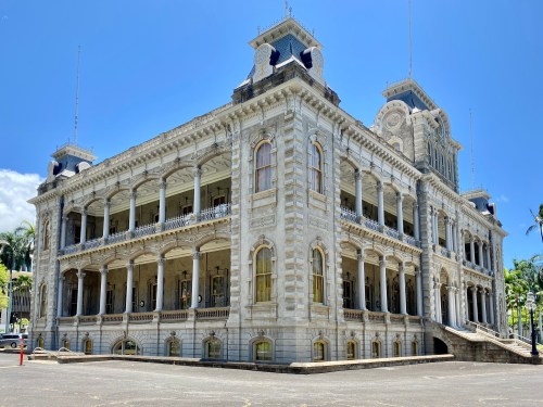 Historic building with ornate architecture, featuring multiple balconies and a grand entrance, set against a clear blue sky.