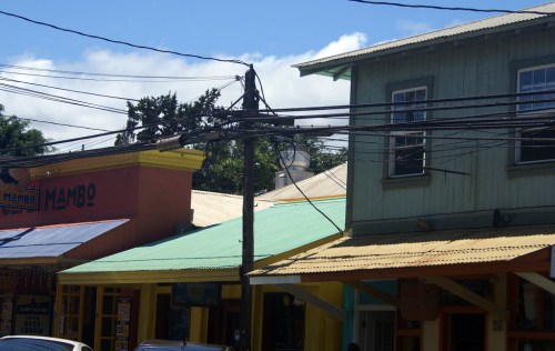 Colorful buildings with metal roofs and power lines against a blue sky.