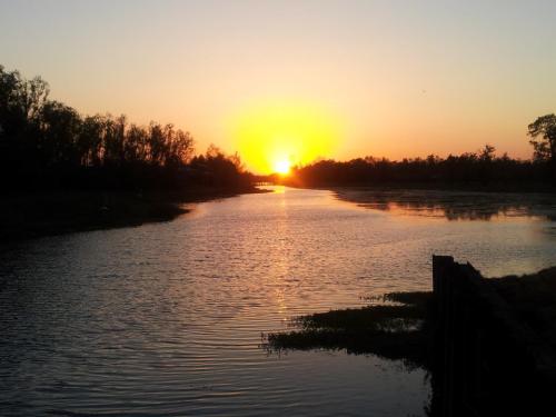 Sunset over a calm river, with silhouettes of trees lining the banks and warm colors reflecting on the water.