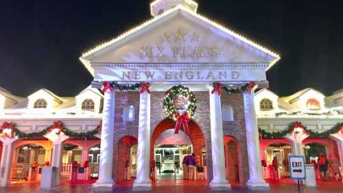 Entrance of Six Flags New England, decorated with holiday lights and a festive wreath, at night.