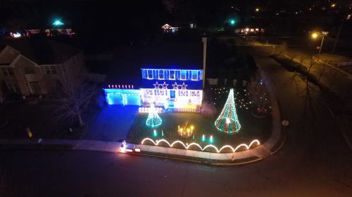 A house decorated with colorful Christmas lights, featuring trees and stars in the yard, glowing in the night.