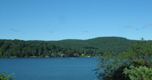 A serene lake surrounded by lush green hills under a clear blue sky.