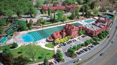 Aerial view of a large pool area with slides, surrounded by greenery, buildings, and a parking lot.