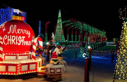 Colorful Christmas lights illuminate a festive scene with decorated trees, Santa figures, and a large "Merry Christmas" sign.