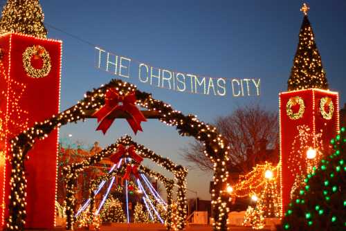 A festive scene featuring illuminated towers and arches adorned with Christmas lights and decorations, labeled "The Christmas City."