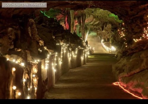A dimly lit cave pathway adorned with colorful lights and natural rock formations.
