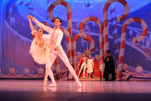 A ballet performance featuring a male and female dancer in elegant poses, with a festive backdrop of candy canes.