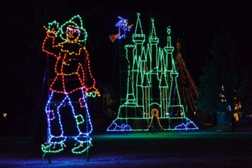 Colorful holiday lights depict a whimsical figure and a castle against a dark night sky.