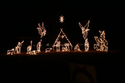 A festive display of illuminated figures depicting a nativity scene against a dark night sky.