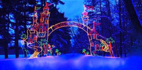 Colorful holiday lights form a whimsical castle archway in a snowy landscape, illuminated against a twilight sky.