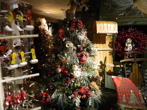 A decorated Christmas tree surrounded by festive ornaments and holiday decor in a cozy shop setting.