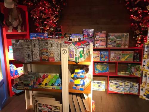 A cozy toy store display featuring colorful games, puzzles, and a detailed toy castle on a wooden table.