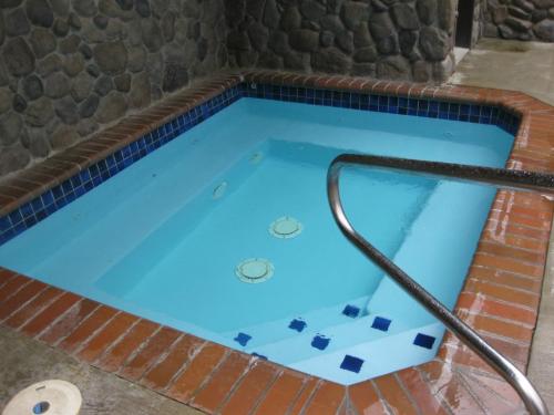 A small, rectangular hot tub with blue water, surrounded by stone walls and brick edging.