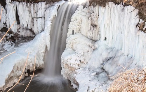 A frozen waterfall cascading over icy cliffs, surrounded by snow and ice formations.