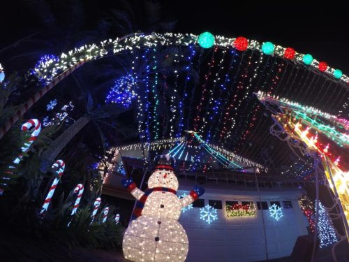 A festive display of colorful holiday lights, featuring a snowman and candy cane decorations in a nighttime setting.